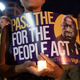 In this July 17, 2021, file photo, a person holds a candle and a poster with an image of the late Rep. John Lewis during a rally in support of voting rights, at Black Lives Matter Plaza in Washington.